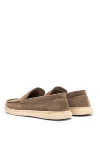 Pantofi slip-on din suede maro, cu vârf rotund, talpă din cauciuc bej și detalii vizibile de cusătură. Textură moale cu un design cu spatele deschis.