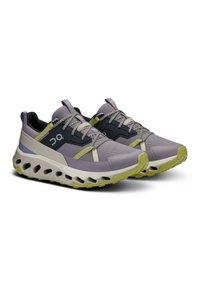 Adidași ușori în nuanțe de mov și bleumarin, cu țesătură din plasă, talpă din cauciuc texturat și accente distinctive verzi la bază.