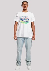 White cotton t-shirt featuring a NASA graphic with a colorful space shuttle design. Paired with light blue denim jeans and white sneakers.