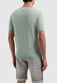 Korte mouwen, geribbelde gebreide shirt in lichtmintgroen, met een ronde halslijn en een soepele textuur. Gecombineerd met lichtgrijze shorts.