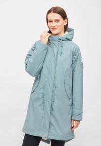 Abrigo impermeable de color azul claro con capucha, con cierre de cremallera, cintura ajustable con cordón, bolsillos laterales y un suave forro de piel cerca del cuello.