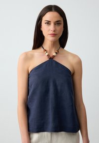 Top halter blu navy realizzato in tessuto leggero, caratterizzato da un design semplice e da un colletto decorativo con perline. Texture morbida e taglio dritto.