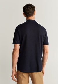 Polo a maniche corte blu navy con colletto classico e tessuto morbido, mostrata di schiena con dettagli essenziali.