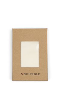 Katoenen stofstaal in een transparante uitsnede, omlijst door een bruin kartonnen achterwand met "GESCHIKT" in het zwart gedrukt.