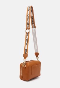 Brun texturerad läderväska med rektangulär form, guldhardware och ett vitt band med "VALENTINO" i svart. Dragkedjestängning och framficka.