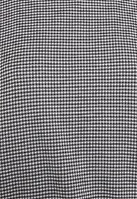Tela de cuadros de gingham en blanco y negro con un patrón de cuadrícula de pequeños cuadrados. El textil tiene una textura suave y un tejido uniforme.