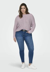 Heledad lilla kootud sviiter ümmarguse kaelusega, kombineeritud tumeda sinise kitsaste teksade ja valgete tossudega. Omab tugevalt kehale järgnev silhouette ja tekstuuri.