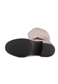 Bota de cuero marrón hasta la rodilla con punta redondeada, superficie texturizada y suela plana de goma negra con un patrón estriado para mayor agarre.