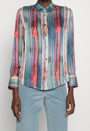 Blouse rayée multicolore avec une texture lisse, un devant à boutons et des détails contrastants aux poignets. Présente des couleurs vives telles que le saphir, le rouge et la crème.