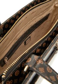 Borsa a mano in pelle nera con finiture dorate e scomparti interni. Foderata con un tessuto beige che presenta loghi "GUESS" ripetuti.