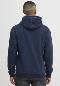 Mornarsko moder dukserica z udobno teksturo, z kapuco, dolgimi rokavi in šivi ob robovih.