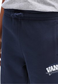 Dunkelblaue Sweatpants mit strukturiertem Finish, ausgestattet mit einem Zugbandbund und einem weißen Vans-Logo auf der unteren linken Seite.