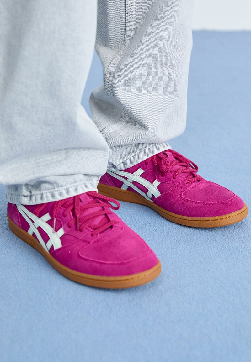 Baskets en suede rose vif avec des accents et des lacets blancs, dotées d'une semelle en caoutchouc et de détails perforés sur la zone des orteils.