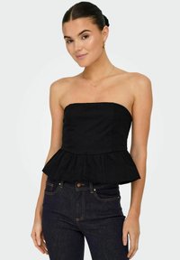 Top negro sin mangas de peplum hecho de tela de algodón, con un busto ajustado y un bajo acampanado, combinado con jeans de mezclilla oscuros.