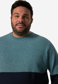 Hellblaues Strickoberteil mit einem strukturierten Muster, versehen mit einem dunkelblauen horizontalen Streifen am Saum. Rundhalsausschnitt, mittlere Gewicht.