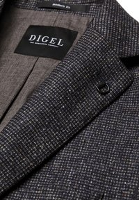 Navy strukturierte Blazer-Innenseite mit einem modernen Passform-Etikett, ergänzt durch ein dezent kontrastierendes braunes Futter und ein schwarzes Akzentknopfdetail.