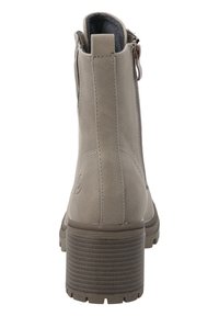 Bottines beiges à finition texturée, fermeture éclair à l'arrière et talon empilé. Elles présentent un discret logo embossé sur le talon.