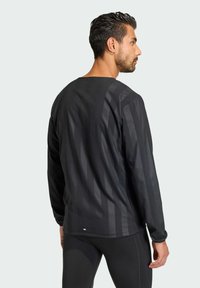 Black long-sleeve shirt with a round neckline, featuring vertical stripes and a smooth texture. The shirt is made of lightweight material.