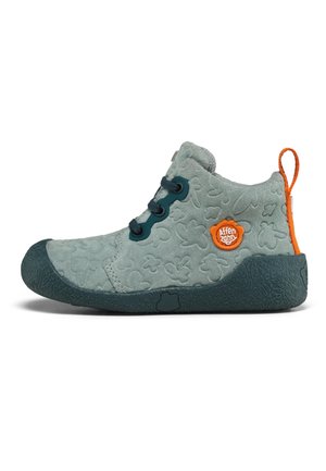 Weicher grauer Kindersuede-Schuh mit eingeprägten Blumenmustern, dunkler Sohle, orangem Zuglasche und orangem Markenlogo an der Seite.