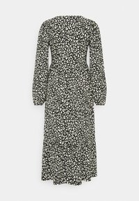 Robe mi-longue à manches longues imprimé léopard noir et blanc, avec une taille cintrée et une jupe évasée, sur fond uni.