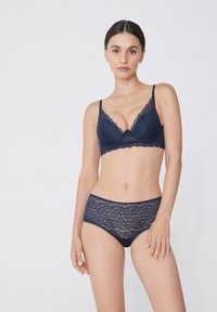 Bralette de encaje azul marino con bordes festoneados y tirantes ajustables, combinado con braguitas de encaje a juego que presentan patrones florales y un acabado suave.