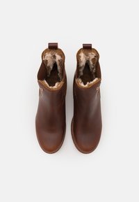 Καφέ δερμάτινα μποτάκια μέχρι τον αστράγαλο με λεία επιφάνεια, πλούσια γούνα εσωτερικά και λεπτομέρειες ραφής, διαθέτοντας θηλιά στο πίσω μέρος για εύκολη εφαρμογή.