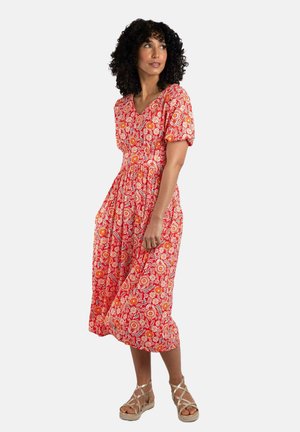 Red floral midi dress with puff sleeves, a V-neck, elastic waist, and white patterned accents. Worn with tan strappy sandals.