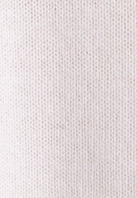 Gros plan d’un tissu en tricot blanc doux avec un motif côtelé et des fils de fil finement texturés.