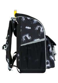 Zaino nero con grafiche di Batman, tasche laterali in rete, dettagli in argento e cerniere grigie. Texture liscia con una forma definita.