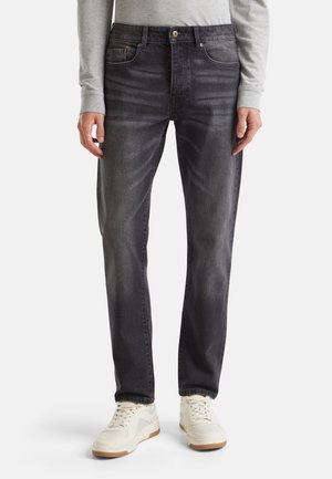 Donkergrijze spijkerbroek met een rechte pasvorm, gemaakt van denim. Heeft subtiele vervaging en een klassiek vijf-pocket ontwerp. Gecombineerd met witte sneakers.