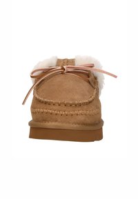 Bruine suède moccasins met een voering van bont, lintaccenten en decoratieve stiksels langs de rand. Platte rubberen zool. Voorzijde.