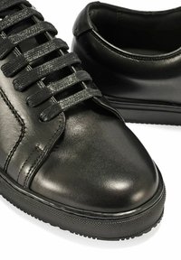 Czarne skórzane sneakersy z sześcioma parami płaskich, plecionych sznurówek, zaokrąglonym noskiem oraz teksturowanymi gumowymi podeszwami o kontrastowym wzorze.