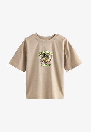 Bežs kokvilnas t-krekls ar īsām piedurknēm, kuram ir karikatūras attēls ar basketbola varoni, kas valkā saulesbrilles, un teksts "SLAM DUNK."