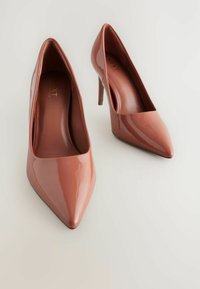 Vaaleanpunaiset patenttiviinilakkakengät, joissa on kärjellinen muotoilu ja 4 tuuman stiletto-korkeudet. Sujuva pinta ja hienovarainen sisämerkintä.
