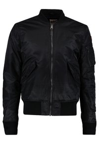 Veste bomber noire avec fermeture éclair à l'avant, deux poches à boutons, col, poignets et taille côtelés, ainsi qu'une poche zippée sur la manche gauche.