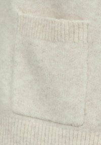 Tejfehér, puha gyapjú textil négyzet alakú folttal és bordázott aljjal. A textúra bolyhosnak tűnik, finom árnyalatváltozásokkal.