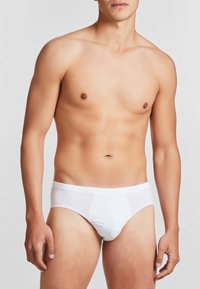 Slip in cotone bianco con un design senza cuciture, morbida texture e una ampia vita elastica. Stile minimalista senza motivi o accenti visibili.