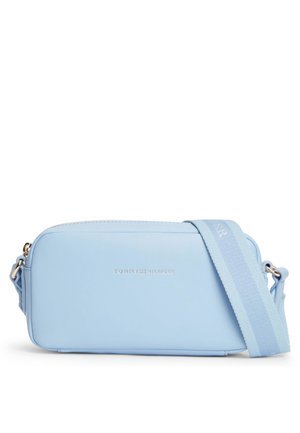 Sac bandoulière rectangulaire bleu clair avec sangle large réglable et petit logo argenté "Tommy Hilfiger" centré sur le devant.