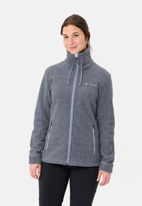 Giacca in pile grigia con colletto alto, chiusura con zip anteriore e due tasche laterali. Presenta zip e logo in grigio chiaro a contrasto sul petto.