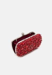 Pochette en satin rouge avec un motif texturé brodé mettant en valeur des accents de type gemme, un fermoir en métal argenté et un doublage en velours.