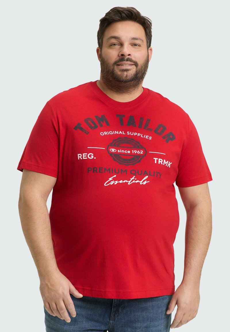 Rode katoenen T-shirt met ronde hals, korte mouwen en een grafisch tekstontwerp in zwart en wit. Draagt met blauwe denim jeans.
