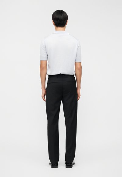 Ανοιχτό γκρι πόλο μπλουζάκι με κοντό μανίκι συνδυασμένο με μαύρο παντελόνι, που αναδεικνύει εφαρμοστό σχέδιο και λεία υφή με καθαρή σιλουέτα.