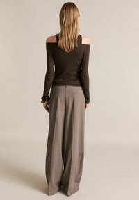 Haut marron décolleté et pantalon gris à jambes larges, avec des poches et une finition texturée. La vue de dos met en avant des lignes fluides et une coupe décontractée.