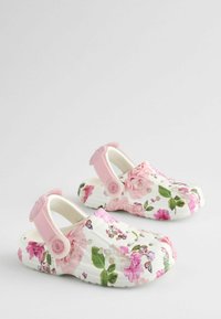 Zoccoli floreali su uno sfondo bianco, con motivi di fiori rosa e viola. Progettati con una fascia posteriore e fori di ventilazione per una migliore traspirabilità.