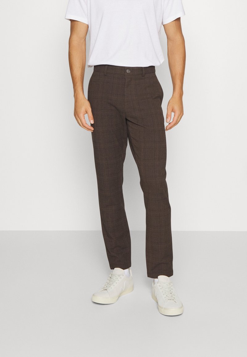 Bruna rutig byxor med skräddarsydd passform och slät textur. Matchade med en enkel vit t-shirt och ljusfärgade sneakers.