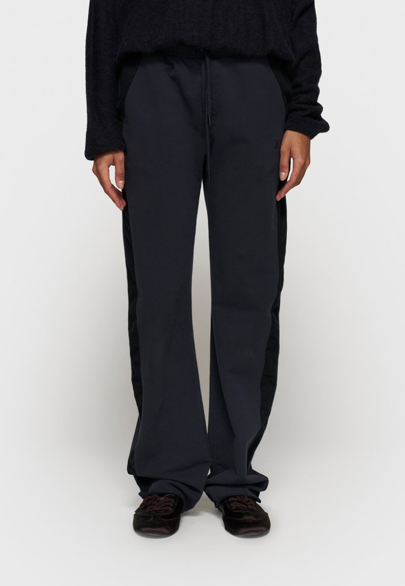 Mørkeblå brede sweatpants med elastisk talje, justerbar snor, sidelommer og kontrasterende sorte sidelapper.