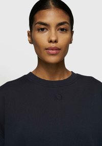 Marine sweatshirt med rund halsudskæring og broderet '10' detalje på forsiden. Blød stoftekstur, afslappet pasform, minimalistisk design.