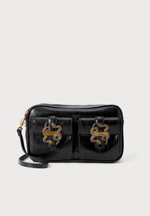 Sac bandoulière en cuir noir avec deux poches avant, chacune équipée d'une fermeture dorée en forme de serpent et une sangle attachée au côté gauche.
