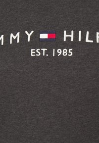 Tmavě šedé bavlněné tričko s vyšitým nápisem "TOMMY HILFIGER" a obdélníkovým logem v červené, bílé a modré barvě s textem "EST. 1985."
