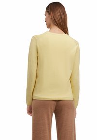 Geel sweatshirt met lange mouwen en ronde hals, zachte textuur en geribbelde manchetten, gecombineerd met een paarse broek. Eenvoudig en casual ontwerp.